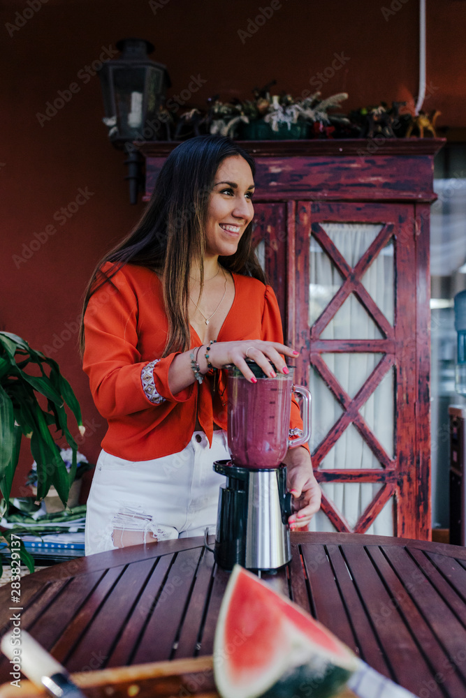 young woman preparing a healthy recipe of diverse fruits, watermelon, orange and blackberries. Using a mixer. Homemade, indoors, healthy lifestyle young woman preparing a healthy recipe of diverse fruits, watermelon, orange and blackberries. Using a mixer. Homemade, indoors, healthy lifestyle