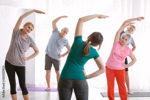 Senior people with young trainer doing exercises in nursing home