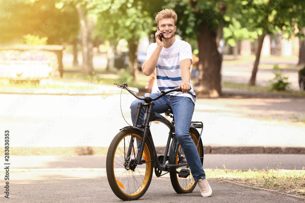 Young man talking by phone while riding bicycle outdoors Young man talking by phone while riding bicycle outdoors