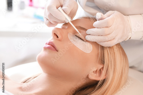 Young woman undergoing procedure of eyelashes lamination in beauty salon photo