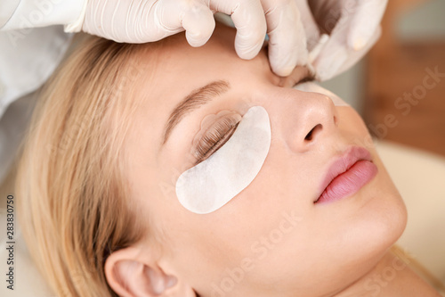 Young woman undergoing procedure of eyelashes lamination in beauty salon