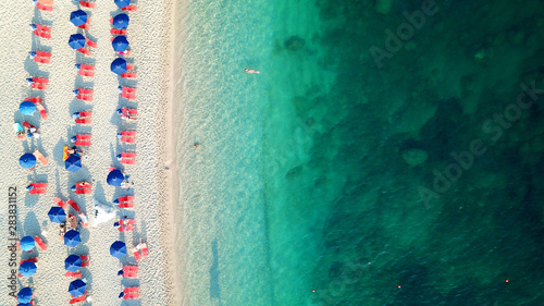 Aerial top view photo of sun beds and umbrellas in popular tropical paradise deep turquoise Mediterranean sandy crowded beach