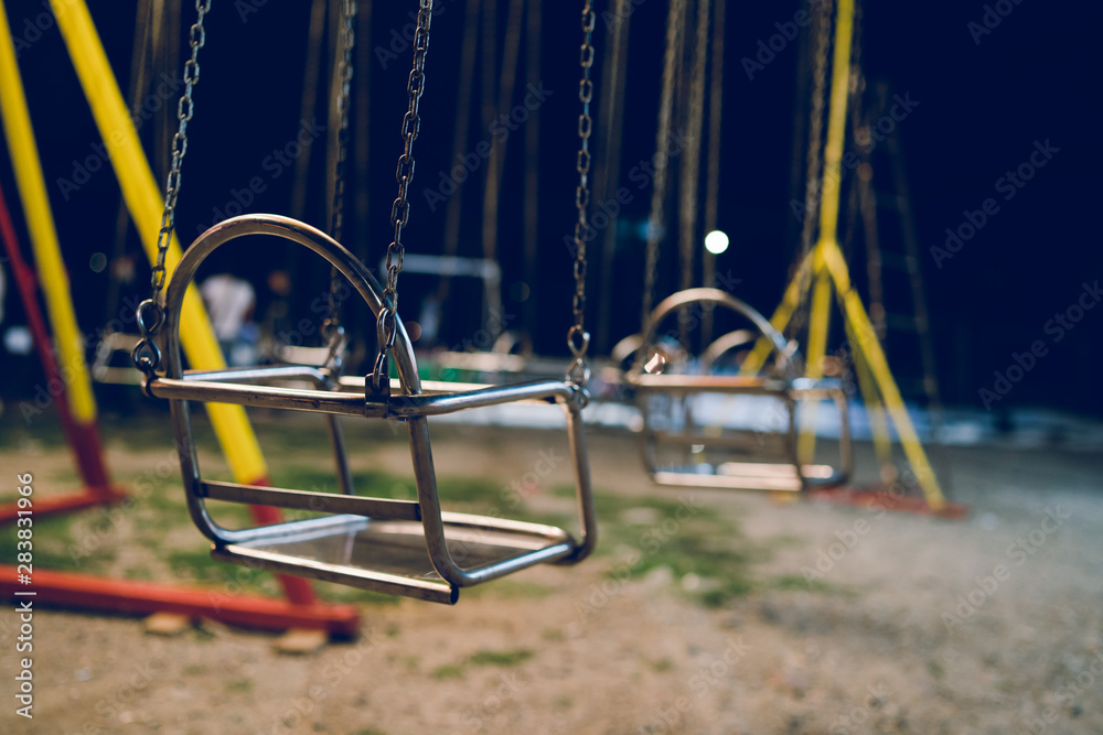 Empty chair on the chains of the swing ride attraction at the fun fair carousel amusement park in the night Empty chair on the chains of the swing ride attraction at the fun fair carousel amusement park in the night