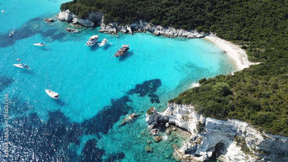 Aerial drone photo of tropical paradise turquoise beach of Voutoumi with sail boats docked in island of Antipaxos, Ionian, Greece