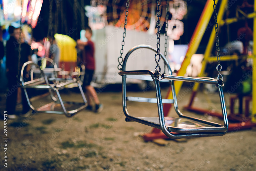 Empty chair on the chains of the swing ride attraction at the fun fair carousel amusement park in the night Empty chair on the chains of the swing ride attraction at the fun fair carousel amusement park in the night