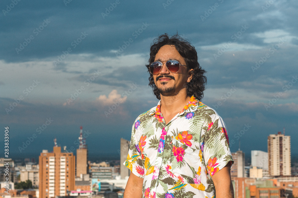 hombre con gafas y camisa colorida mirando la ciudad