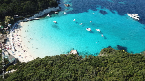 Aerial drone photo of beautiful exotic paradise turquoise sandy beach of Voutoumi with sail boats docked in island of Anti paxos, Ionian, Greece