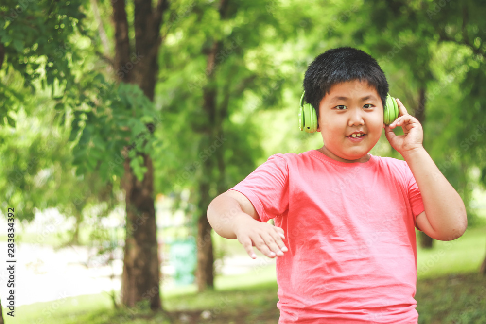 Asian children wear headphones, green music, fun with music in the garden.