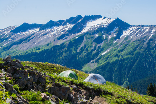 tents on meadow hillside below rocky mountain range Glacier Peak Wilderness