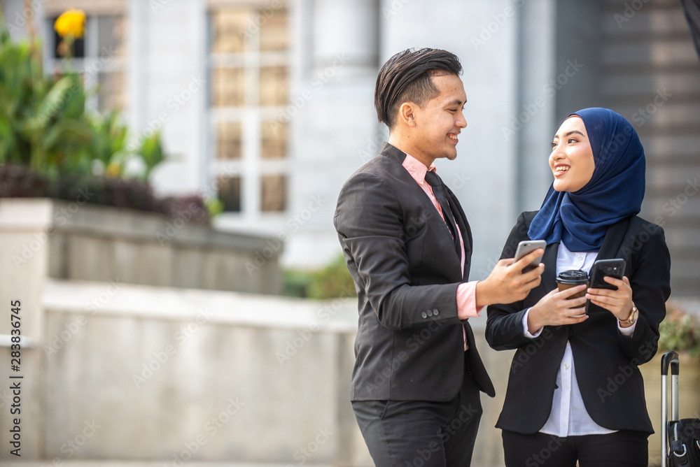 Muslim Businessman and Businesswoman having a conversation during a coffee break. Outdoor scene.