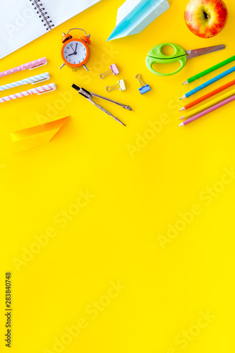 Creative mess on student's desk on yellow background top view mockup