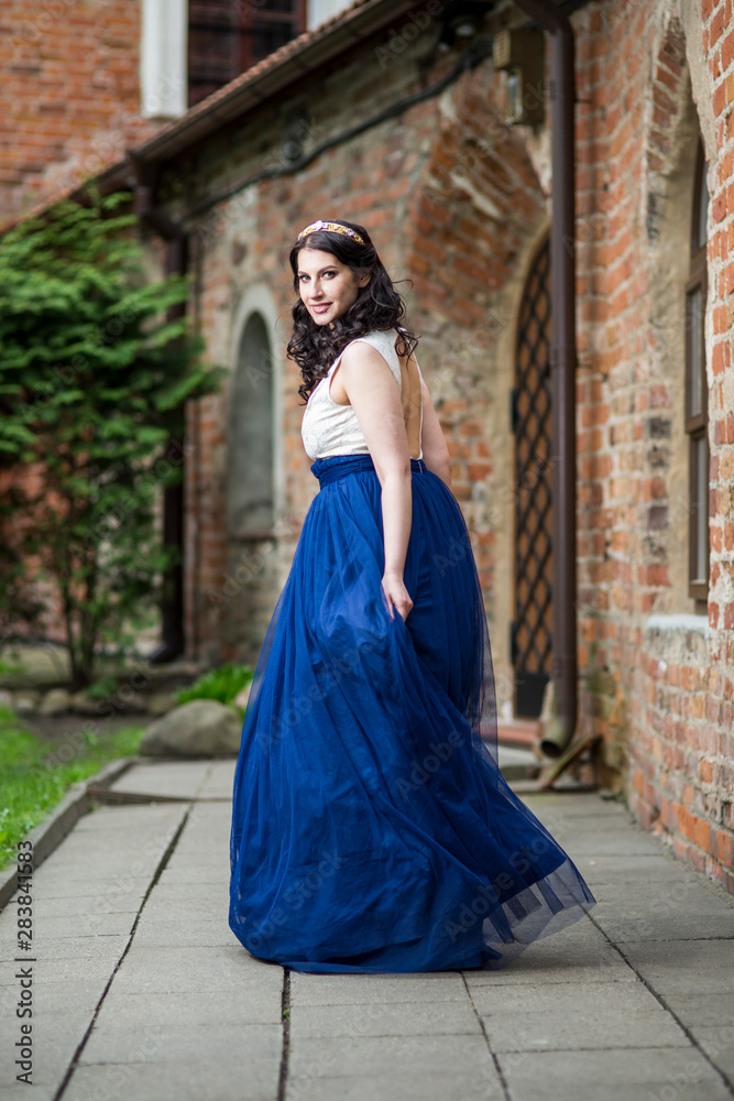 Naklejka premium Portrait of Sensual Young Brunette Lady Dancing in Long Blue Dress. Wearing Tiara.