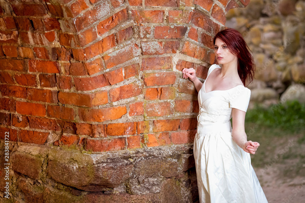 Portrait of Red-Haired female Against Ancient Brick Wall Outdoors. Portrait of Red-Haired female Against Ancient Brick Wall Outdoors.