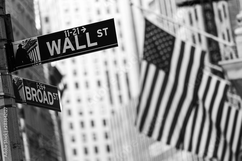 Wall street sign in New York City with American flags and New York Stock Exchange in background. Black and white image. photo