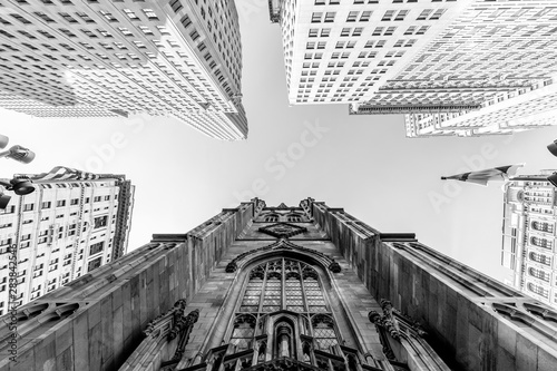 Photography Wide angle upward view of Trinity Church at Broadway and Wall Street with surrounding skyscrapers, Lower Manhattan, New York City, USA