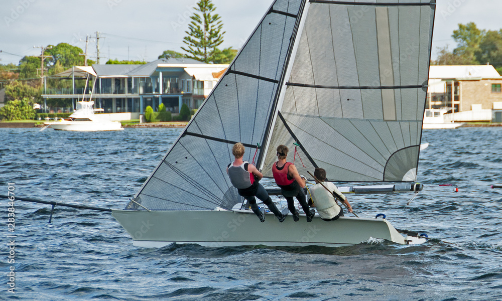 Fototapeta premium High school teens Sailing small sailboat with a Strong Wind on a lake. Lake Macquarie, Australia.