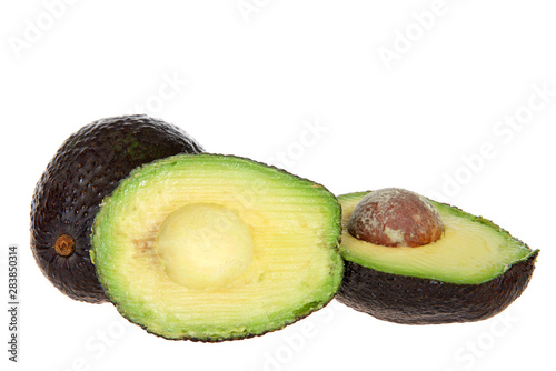 whole avocado and one cut with seed exposed, isolated on white background. Avocados are grown commercially in parts of Florida, California and Hawaii.