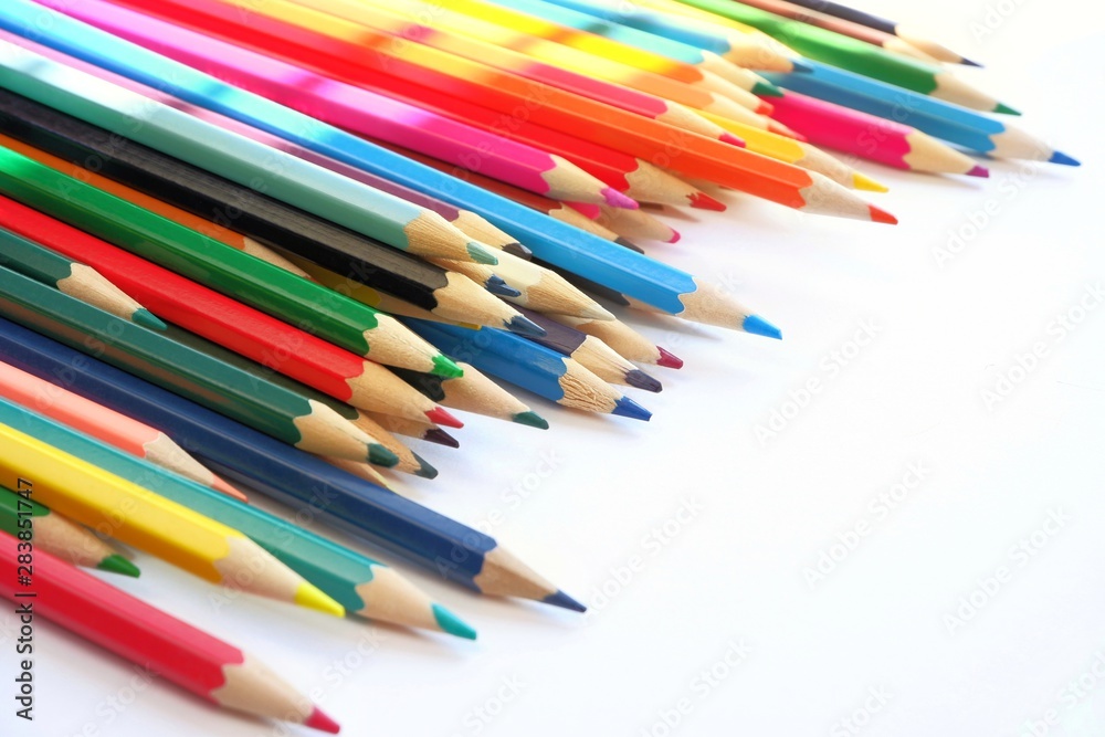 The sun's rays fall on the colored pencils lying on a white background. Color Therapy Concept.Copy space for text, with selective focus. The sun's rays fall on the colored pencils lying on a white background. Color Therapy Concept.Copy space for text, with selective focus.