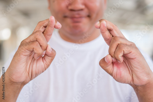old asian man crossing finger, wishing for good luck