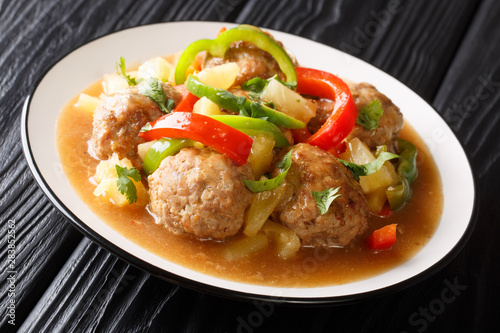 Asian meatballs stewed with fresh pineapples and bell pepper in sweet and sour sauce close-up on a plate. horizontal