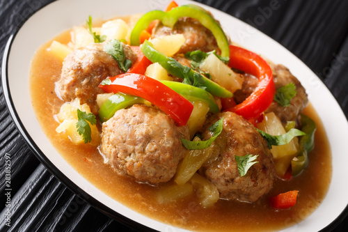 Meatballs cooked with fresh pineapples and vegetables in a sweet and sour sauce closeup on a plate. horizontal