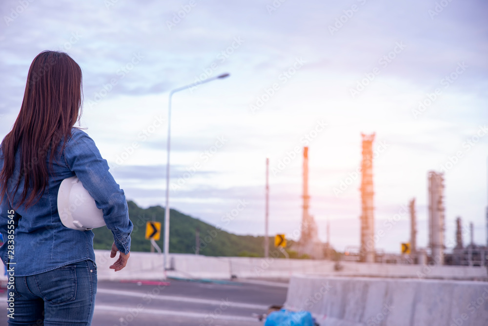 Woman Engineer and safety Officer concept.Young woman engineer wear safety hat (helmet) and blue jean.Safety Officer  inspector in front of refinery plant.