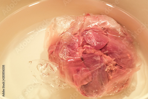 Defrosting meat in water. Frozen liver.