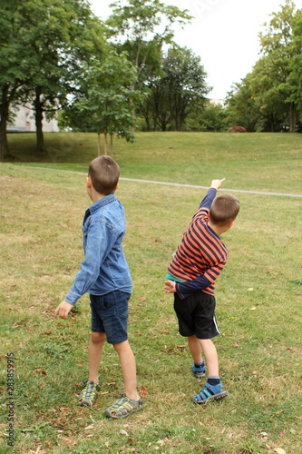 two boys stand with their backs in the park, show their hand forward © kittyfly