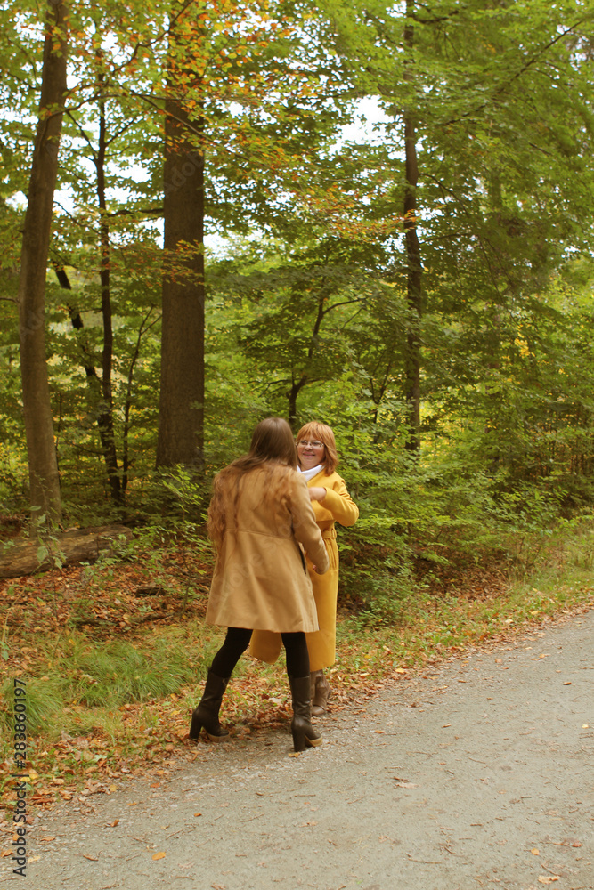 two people, mother and daughter, a woman and a young girl holding hands, dancing in a yellow autumn park, concept of family relationships, generation