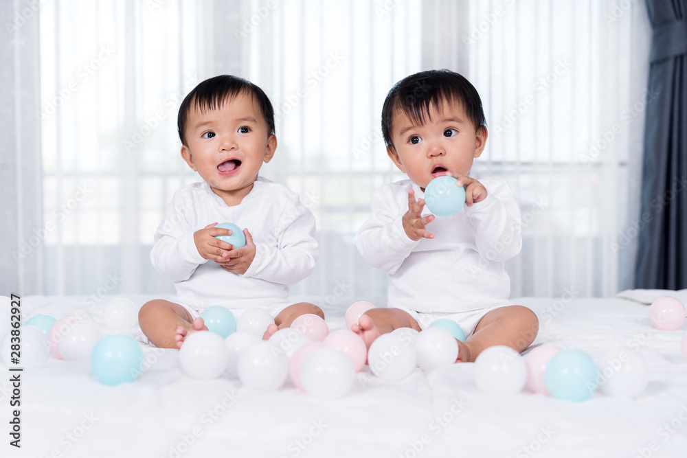 cheerful twin babies playing color ball on bed cheerful twin babies playing color ball on bed