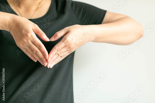 Wallpaper Mural A woman use hands display love symbol by splice fingertips together to be heart shape at front of left chest. Torontodigital.ca