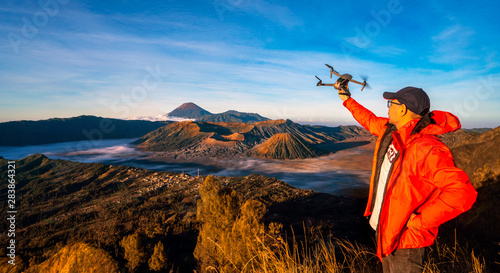 photographer on the top of mountain to take a sunrise photo by drone for Bromo vocano photo