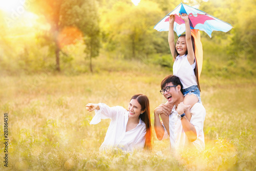 Asian family father, mother and daughter play ta kite in the outdoor park photo