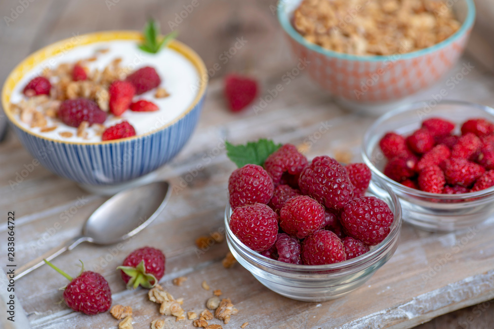 Bowls with berries, yogurt, granola on a wooden tray. Bowls with berries, yogurt, granola on a wooden tray.