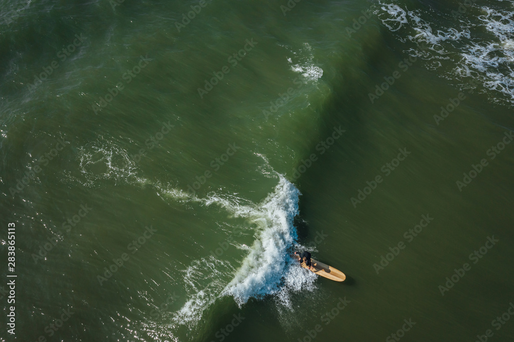 Aerial view on surfer in the sea, surfer catching waves in baltic sea.