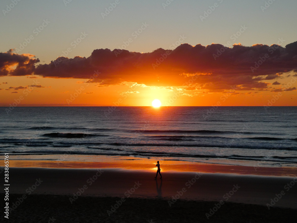 A vibrant dawn as the sun comes up over the ocean on Coolum Beach on the Sunshine Coast, Queensland, Australia A vibrant dawn as the sun comes up over the ocean on Coolum Beach on the Sunshine Coast, Queensland, Australia