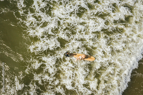 Aerial view on surfer in the sea, surfer catching waves in baltic sea.