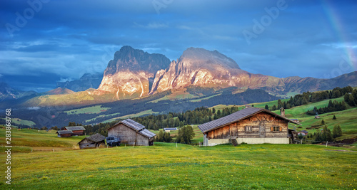 Alpe di Siusi - Seiser Alm with Sassolungo - Langkofel mountain group in background at sunset. Wooden chalets in Dolomites, Trentino Alto Adige, South Tyrol, Italy, Europe