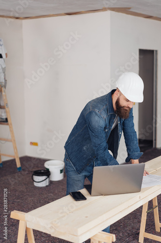 Builder working on a laptop on site