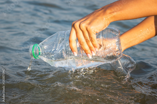 Plastic bottle being picked from the sea, planet pollution concept