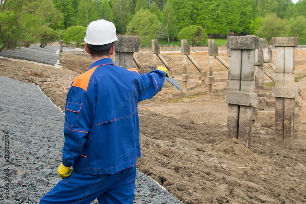 worker in blue uniform and white helmet, with a tablet in his hands, exploring the area under construction worker in blue uniform and white helmet, with a tablet in his hands, exploring the area under construction
