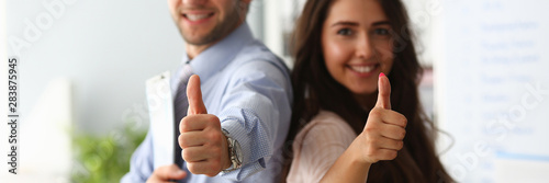 Businessman and business woman hold thumbs up