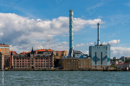 Cityscape skyline view of a blue power plant among residential buildings in the city of Gothenburg Sweden seen from the sea.