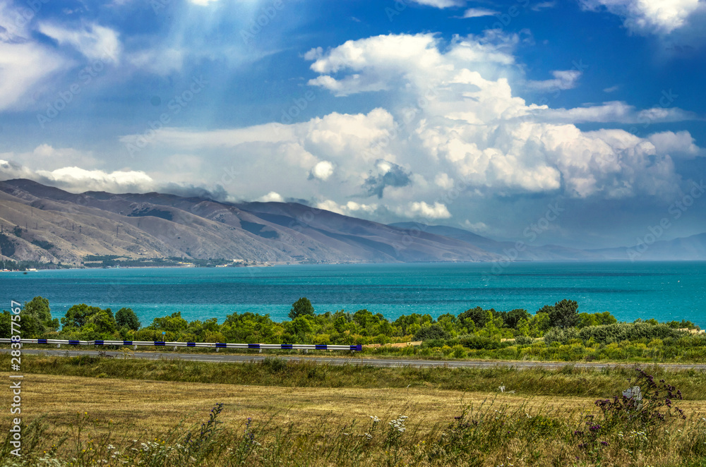 High-mountain lake Sevan, surrounded by the mountains of Geghama, is covered with thick clouds view from the road passing along the coast