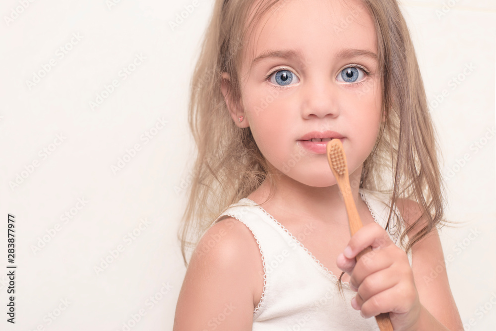 Little girl holding a bamboo toothbrush in her hands. Dental health concept.Copy space Little girl holding a bamboo toothbrush in her hands. Dental health concept.Copy space