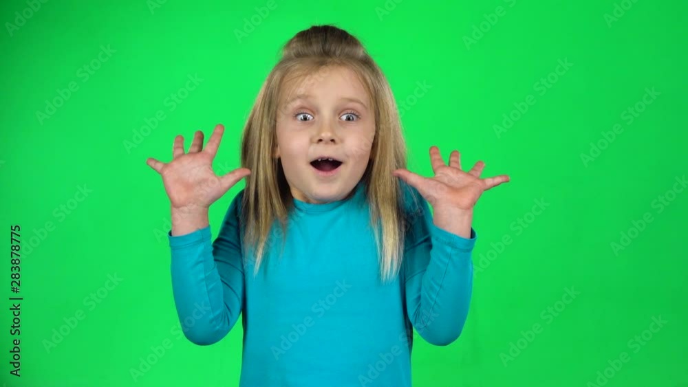 Funny child posing shows frightened emotion on green background. Slow motion Funny child posing shows frightened emotion on green background. Slow motion