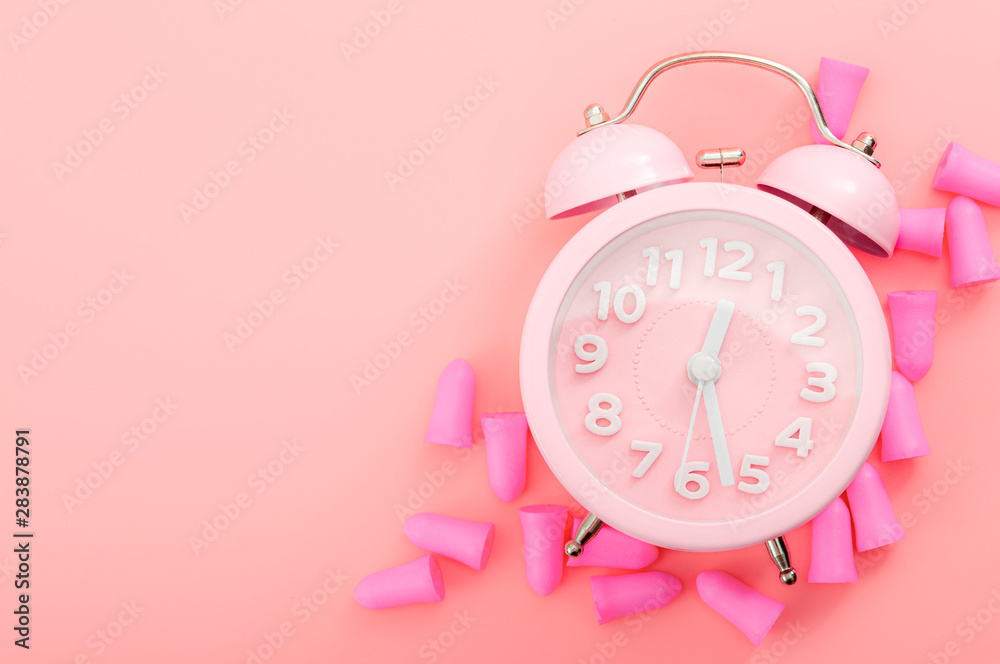 Restful sleeping, wear ear plugs and how to hear the alarm clock without missing sleep due to noise concept theme with earplugs and vintage clock isolated on pink background with copy space Restful sleeping, wear ear plugs and how to hear the alarm clock without missing sleep due to noise concept theme with earplugs and vintage clock isolated on pink background with copy space