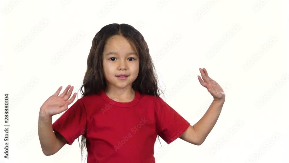 Little dark-haired girl waving with hands on white background. Slow motion Little dark-haired girl waving with hands on white background. Slow motion
