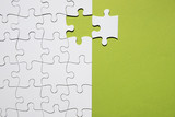 White puzzle piece separate with white puzzle grid on green backdrop