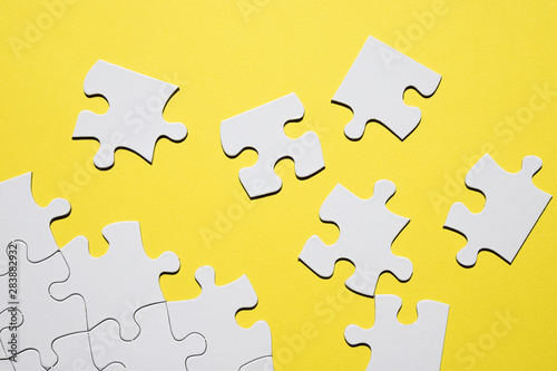 Separate white puzzle piece on yellow backdrop